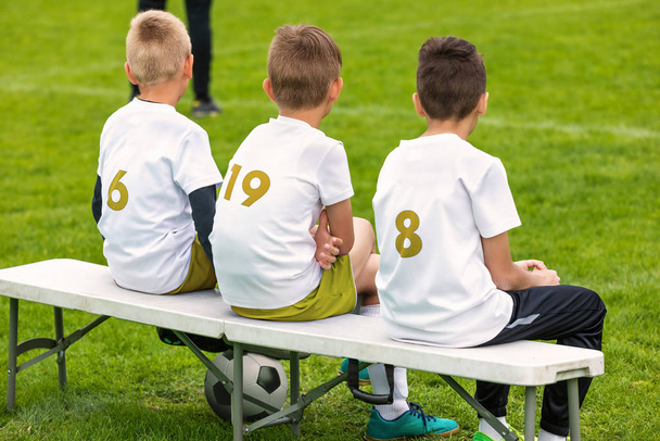 A fiúk a sport focicsapatban egy helyettesítő padon ülnek. Junior szintű sportverseny Outfoor Tournament. Vissza Kilátás a labdarúgó padra - Fotó, kép