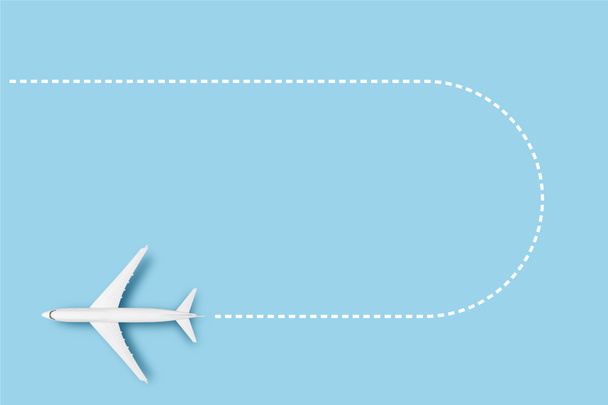 Vliegtuig en lijn die de route aangeven op een blauwe achtergrond. Concept reizen, vliegtickets, vlucht, route pallet. Een spandoek. Vlakke lay, bovenaanzicht. - Foto, afbeelding