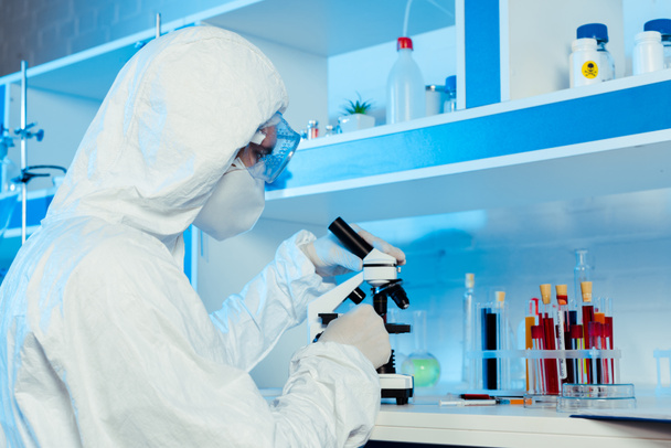 scientist in hazmat suit and goggles near microscope  - Fotoğraf, Görsel