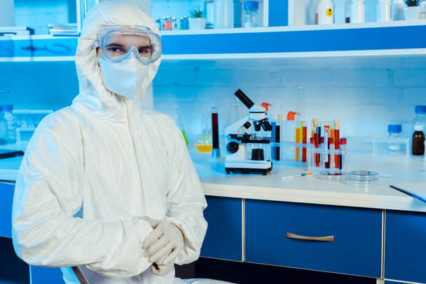 учёный в защитном костюме и очках, стоящих возле микроскопа
  - Фото, изображение