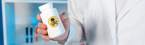 πανοραμική βολή του επιστήμονα κρατώντας μπουκάλι με τοξικό σύμβολο  - Φωτογραφία, εικόνα