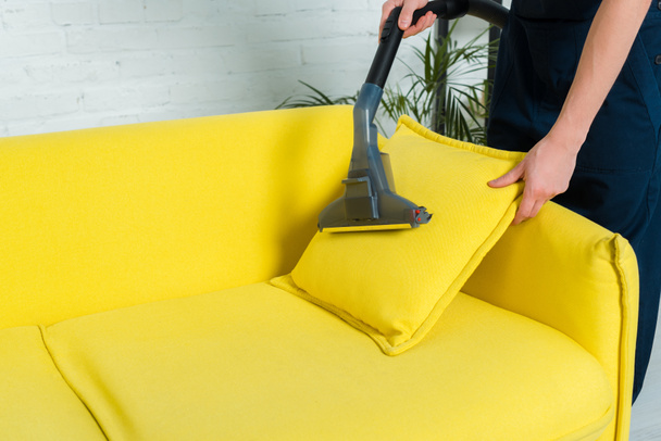 cropped view of man removing dust on pillow with vacuum cleaner  - Foto, afbeelding