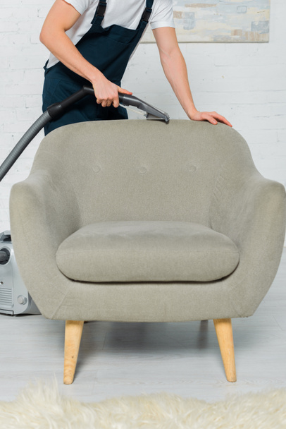 cropped view of cleaner in uniform dry cleaning armchair with vacuum cleaner  - Φωτογραφία, εικόνα