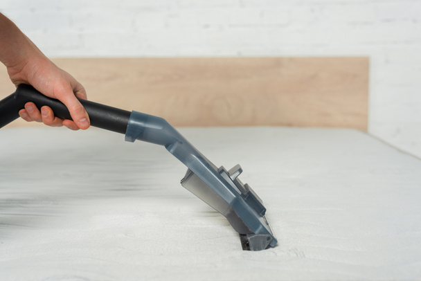 cropped view of cleaner removing dust on mattress in bedroom with vacuum cleaner  - Photo, Image