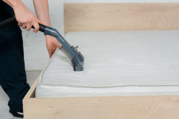 oříznutý pohled na čistič držící vysavač při čištění matrace  - Fotografie, Obrázek