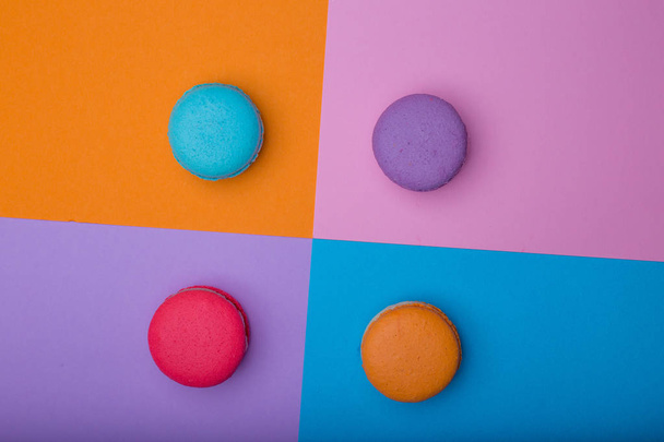 Sweet colorful macaroons on multicolored square background. Pink, blue, orange and purple cookies. Horizontal, top view - Valokuva, kuva
