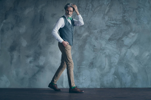 Full length photo of senior macho business man check neat hairstyle walk corporate meeting wear specs shirt waistcoat pants green tie shoes isolated concrete grey color wall background - Fotó, kép