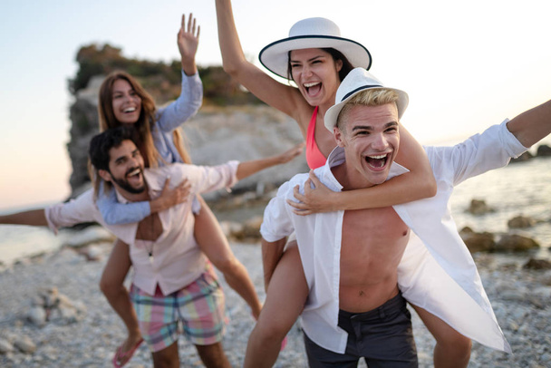 Skupina šťastných přátel baví na pláži při západu slunce na dovolené - Fotografie, Obrázek