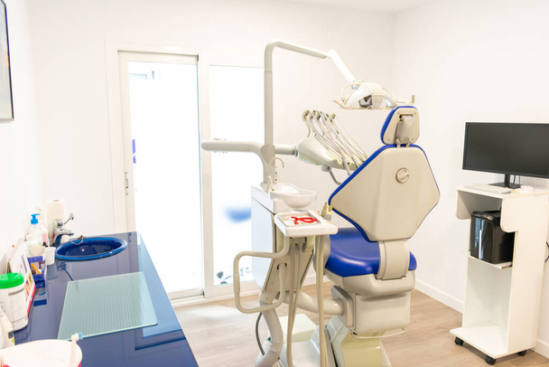 μια μπλε οδοντιατρική πολυθρόνα σε οδοντιατρική κλινική με λευκούς τοίχους - Φωτογραφία, εικόνα