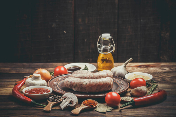Many different spices, vegetables and ingredients, and fresh raw barbecue sausages for the family. - Foto, imagen