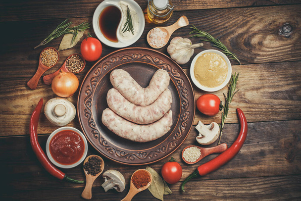 Many different spices, vegetables and ingredients, and fresh raw barbecue sausages for the family. - Foto, Imagen