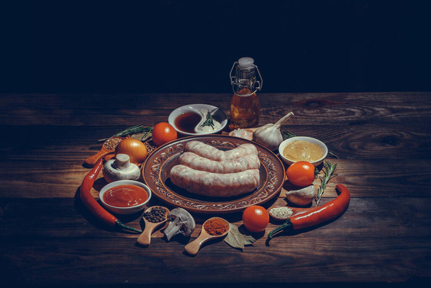 Many different spices, vegetables and ingredients, and fresh raw barbecue sausages for the family. - Foto, immagini