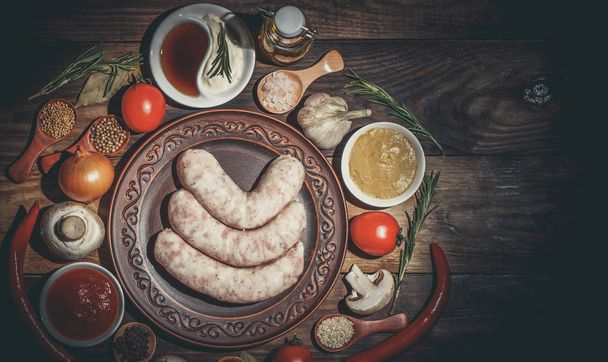 Many different spices, vegetables and ingredients, and fresh raw barbecue sausages for the family. - Valokuva, kuva
