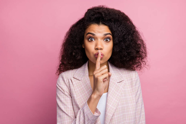 Hush private novelty. Astonished marketer afro american girl put index finger lips dont tell managers company speechless secrets wear plaid stylish jacket suit isolated pastel pink color background - 写真・画像