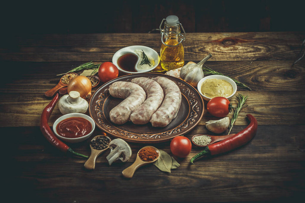 Many different spices, vegetables and ingredients, and fresh raw barbecue sausages for the family. - Фото, зображення