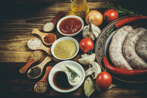 Many different spices, vegetables and ingredients, and fresh raw barbecue sausages for the family. - 写真・画像