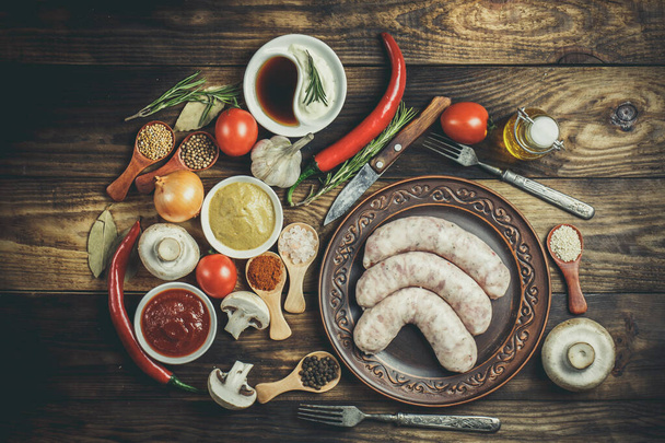 Many different spices, vegetables and ingredients, and fresh raw barbecue sausages for the family. - Foto, Imagem