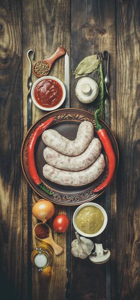 Много различных специй, овощей и ингредиентов, и свежие сырые сосиски барбекю для семьи
. - Фото, изображение
