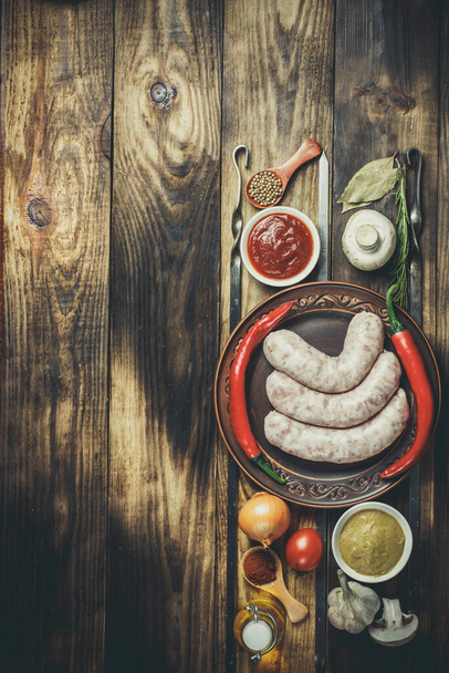 Many different spices, vegetables and ingredients, and fresh raw barbecue sausages for the family. - Fotó, kép