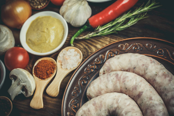 Много различных специй, овощей и ингредиентов, и свежие сырые сосиски барбекю для семьи
. - Фото, изображение