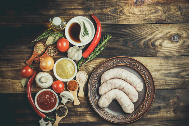 Many different spices, vegetables and ingredients, and fresh raw barbecue sausages for the family. - Fotó, kép