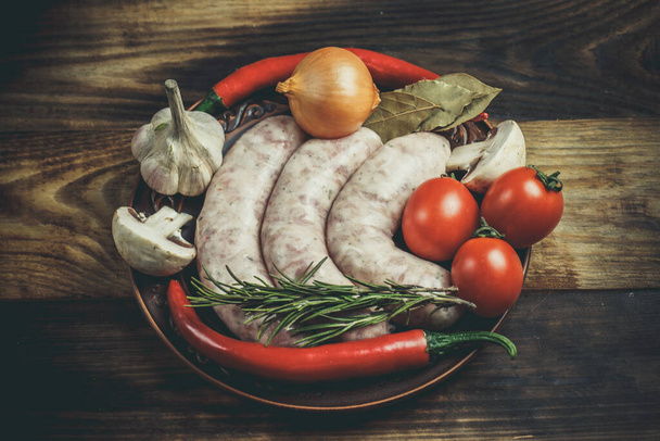 Many different spices, vegetables and ingredients, and fresh raw barbecue sausages for the family. - Foto, immagini
