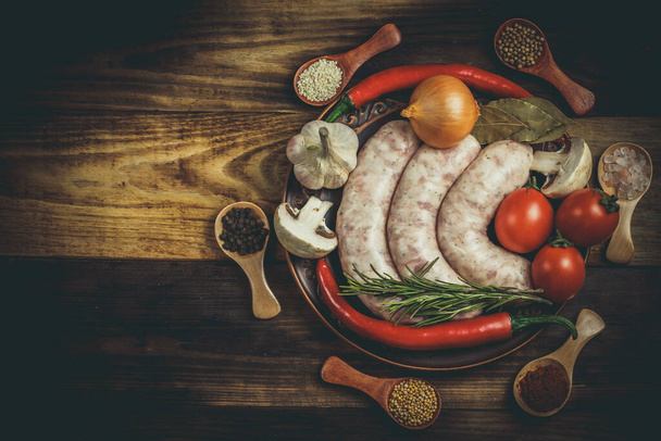 Many different spices, vegetables and ingredients, and fresh raw barbecue sausages for the family. - Foto, Bild