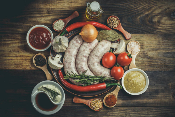 Many different spices, vegetables and ingredients, and fresh raw barbecue sausages for the family. - Фото, изображение