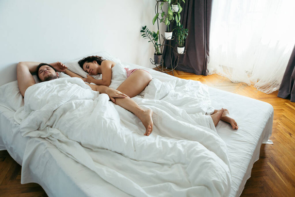 paar slapen in bed met witte lakens kopiëren ruimte - Foto, afbeelding