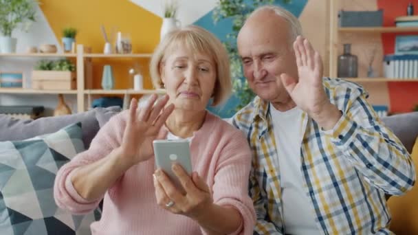 Elderly people making online video call talking showing thumbs-up holding smartphone - Materiaali, video