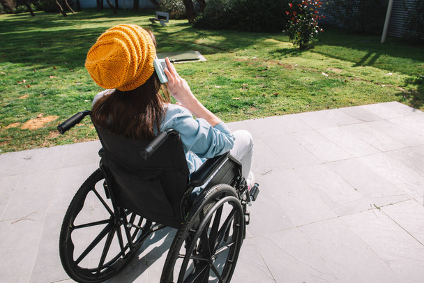 Tekerlekli sandalyedeki engelli kız cep telefonuyla konuşuyor. Engelli ve teknoloji kavramı. - Fotoğraf, Görsel