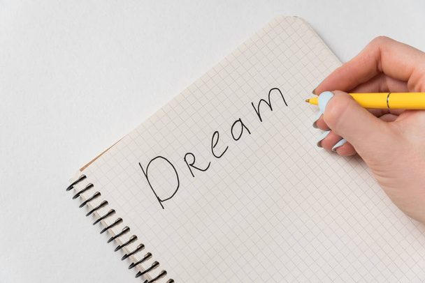 Word Dream escrito en el cuaderno. Escritura manual femenina en bloc de notas. Lista de deseos
. - Foto, imagen