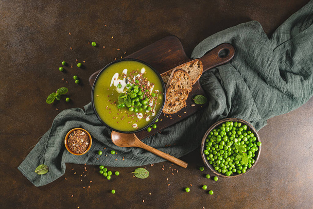 Green pea soup with linseed and pumpkin and sunflower seeds on a rustic kitchen countertop. - Photo, image