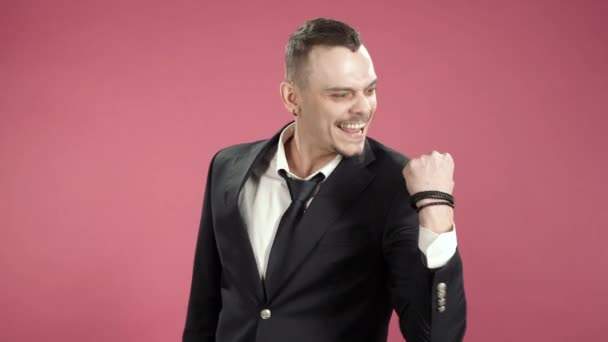 Young man hipster in a suit joyfully showing yes gesture on camera over pink background. - Imágenes, Vídeo