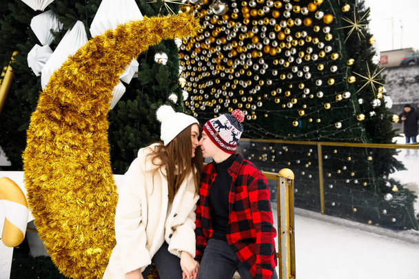 Şehir buz pateni pistinde öpüşen mutlu aşıklar ve Noel ağacı arka planı - Fotoğraf, Görsel
