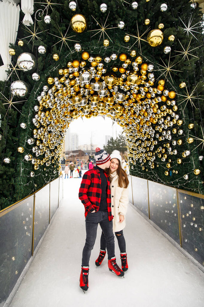 beautiful young couple of lovers standing on ice rink and decorated Christmas tree background - Foto, Imagen