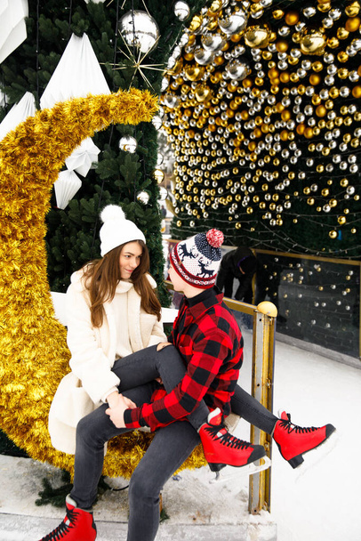 笑顔と幸せなカップルの男の子と女の子のポーズクリスマス飾りの木とアイスリンクの背景 - 写真・画像