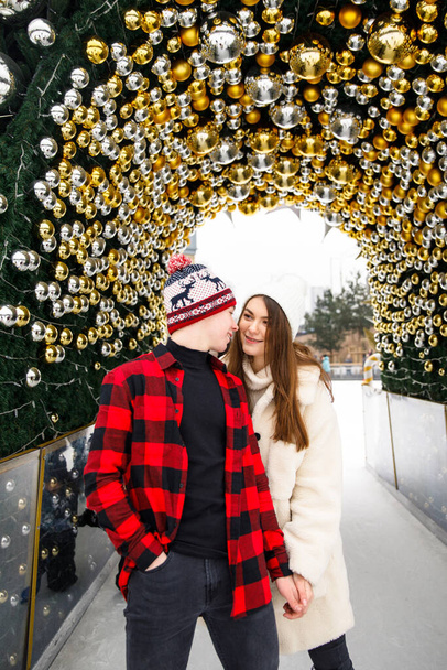 portraits of boy and girl standing near decorated Christmas tree on ice rink background - Foto, afbeelding