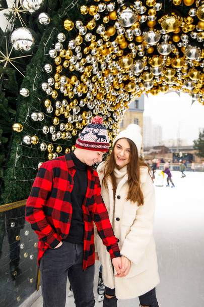 portraits of boy and girl standing near decorated Christmas tree on ice rink background - Foto, Bild
