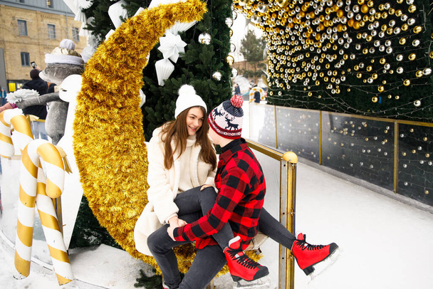 smiling and happy couple of boy and girl posing Christmas decorated tree and ice rink background - Photo, Image
