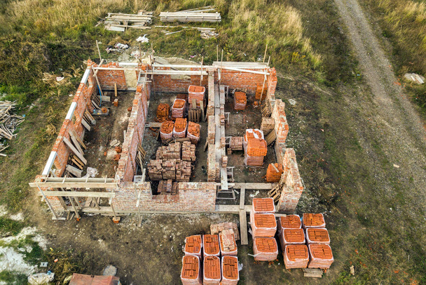 Aerial view of building site for future brick house, concrete foundation floor and stacks of yellow clay bricks for construction. - Photo, Image