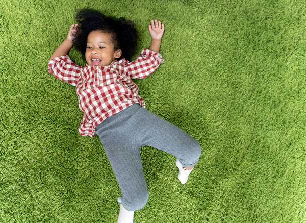 Happy children kids smiling and laying on green carpet floor in living room at home. - Фото, изображение