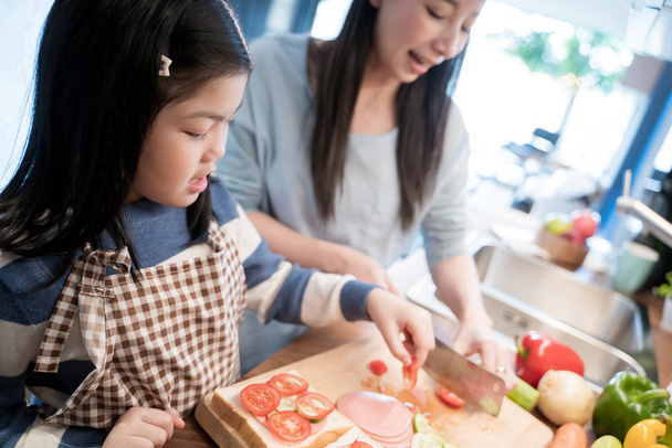 Daughter and mother preparing the sandwich and salad for breakfast in kitchen. - Foto, imagen