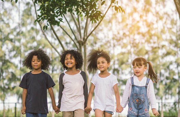 子供の友情一緒に笑顔の幸福コンセプトかわいいアフリカ系アメリカ人の男の子と女の子が夏の晴れた日に手を取り合って歩く - 写真・画像
