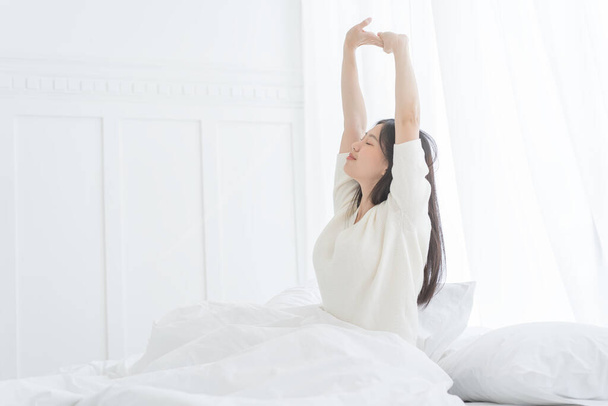 Young Asian woman in the morning she stretching in her bed in the bedroom - Foto, Imagen