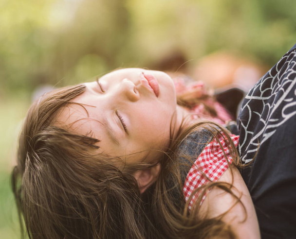 Sleeping little girl on mother shoulder in nature park - Zdjęcie, obraz