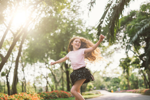 young girl with arms open enjoying her freedom at the park so happy relax dance - Photo, Image