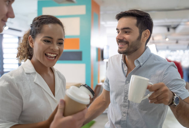 Ділові люди розмовляють і тримають чашки кави. Група колег, які мають кавову перерву в офісі
. - Фото, зображення