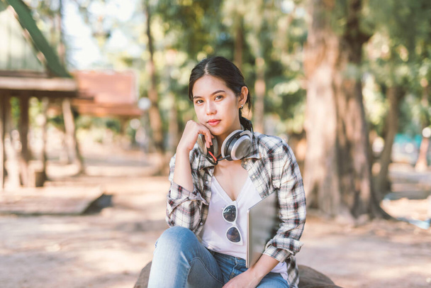 portrait of Asian girl student with laptop headphones in park - Photo, Image