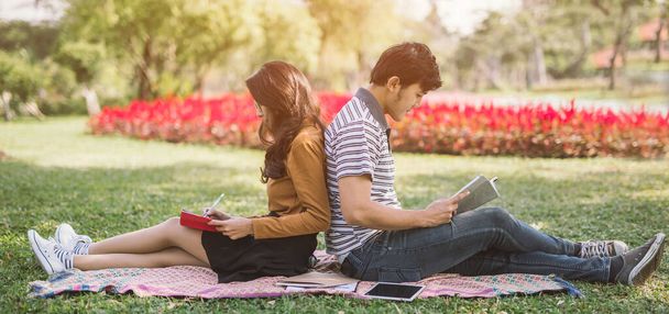 Asian couples reading a book .Campus life. Couple of students with a books. Education in nature park - Zdjęcie, obraz
